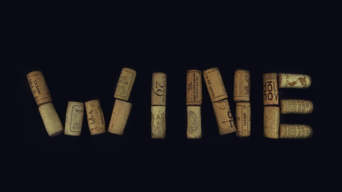 Wine corks arranged to spell 'WINE' against a black background, showcasing creativity and elegance.